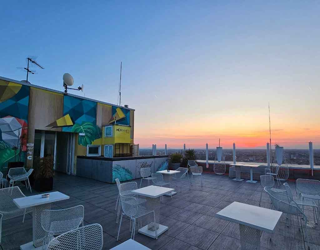 Blind Spot Venice : bar-terrasse sur le toit offrant une vue sur le coucher de soleil sur la ville et des tables en terrasse